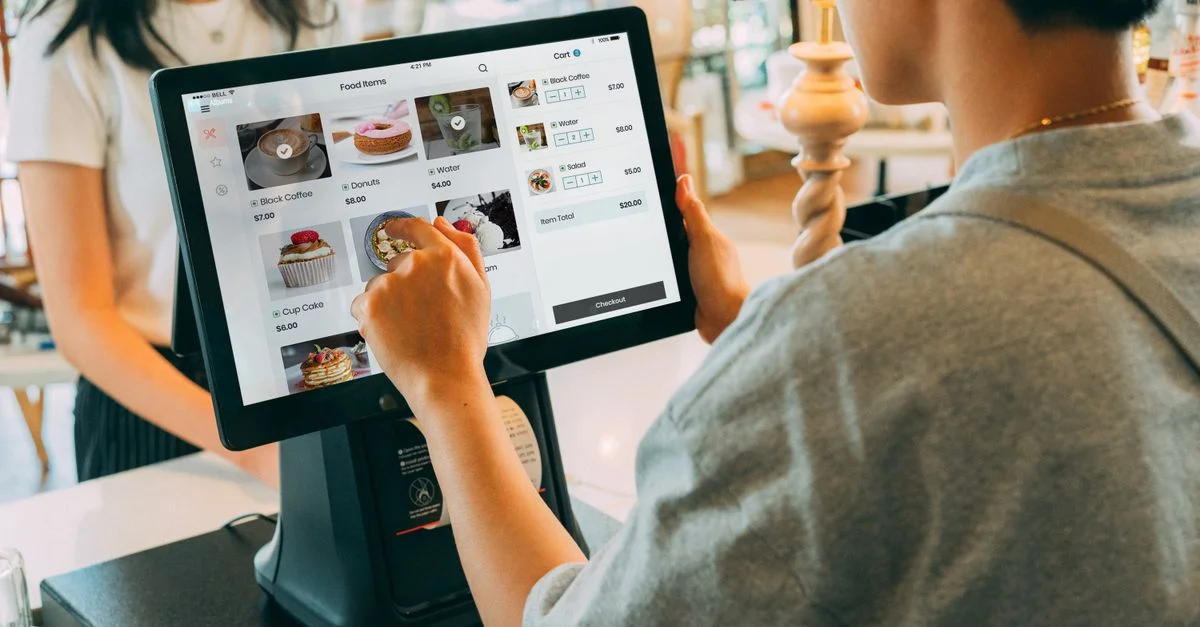 Un client utilisant un système à écran tactile au comptoir d'un café pour un traitement de paiement moderne.