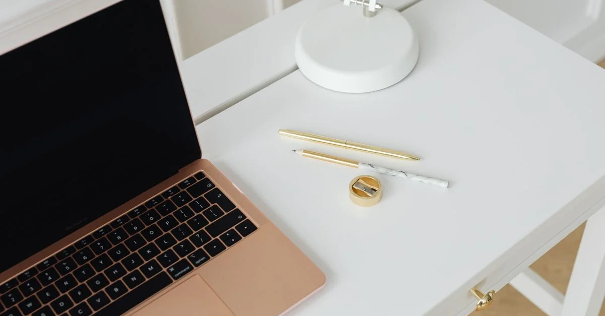Un bureau propre et minimaliste avec un ordinateur portable, des stylos et une lampe, parfait pour les espaces de travail.