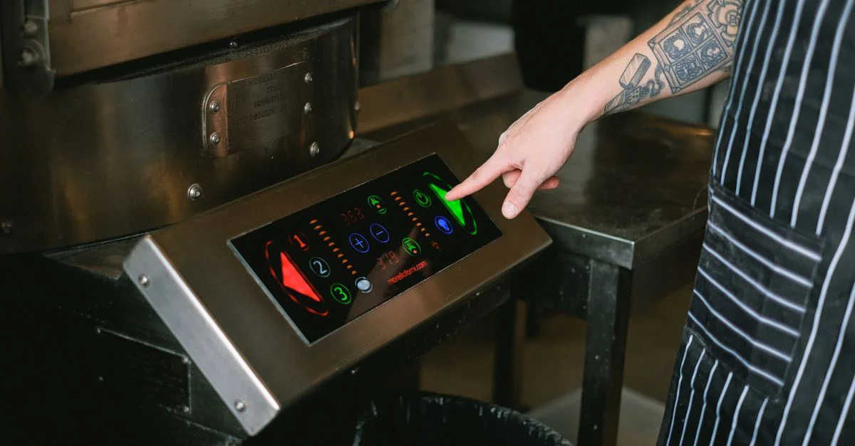 Gros plan d'un chef utilisant un panneau de contrôle à écran tactile dans une cuisine moderne.